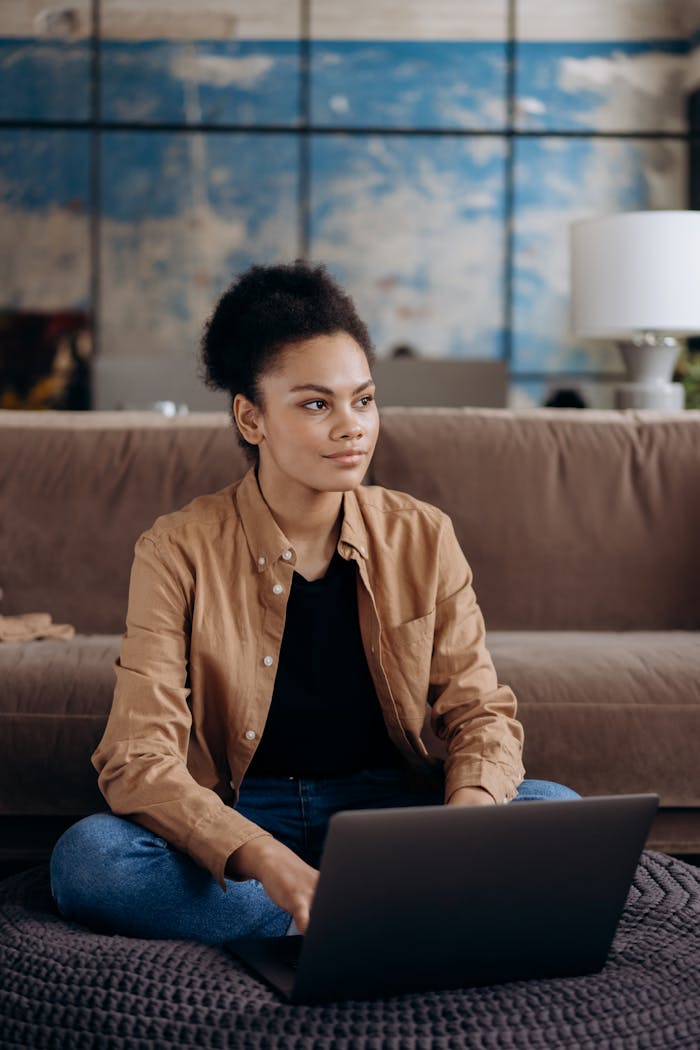Young woman using laptop at home, focusing on work in a casual and cozy setting.